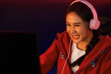 Portre sunucusu güzel Asyalı kız flamasının çevrimiçi oyun oynaması kulaklık takması pastel renkli konuşmalar izleyici medyası ile çevrimiçi. Esport yetenekli takım oyuncuları neon mavi odada. Taktik.