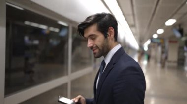 Profesyonel iş adamı tren istasyonunda dikilirken kameraya gülümser. Beyaz yetenekli yönetici kameraya bakarken kendine güvenen bulanık bir geçmişi var. Sevinçli..