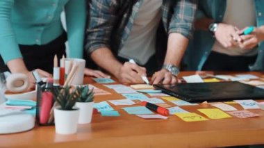 Dizüstü bilgisayara bakan ve logo tasarımını işaret eden yetenekli bir iş ekibi ana tema rengini seçme ve pazarlama kampanyasını planlama kararı alıyor. Birlikte çalışan akıllı bir grup. Sempozyum.