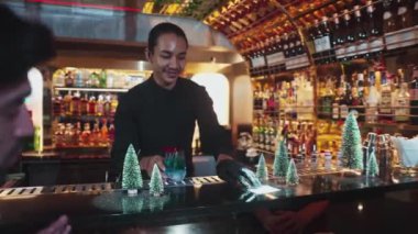 Barmen, kırmızı kurutulmuş meyve biberiyesiyle mavi lagün kokteyli servis ediyor. Lüks barın üzerinde, arkadaşının ya da yeşil neon karlı Noel ağacı festivalinde bir çiftin yanında tatmakta olan güzel bir kadına. Vinosity.