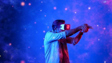 Yetenekli oyuncular silah olarak el ele tutuşup VR gözlük takıp atış oyunu oynayarak metaevrene girebiliyor. Çekici erkek model mavi arka planda dururken hareket ediyor ve oyuncuyu hedef alıyor. Aygıt.