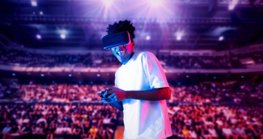Yetişkinlerin elinde joystickle VR gözlükleri varken stadyumda arka planda bulanık oyunlar oynamaktan zevk alıyorlar. Afrikalı adam kontrol etmeyi ve artırılmış gerçeklik teknolojisini kullanmayı seviyor. Yaratıcılık.