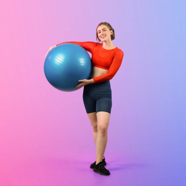 Vücut uzunluğunun tamamı atletik ve sportif genç bir bayanın izole edilmiş arka planda duran bir duruşta topa egzersiz yapmasıyla geçiyor. Sağlıklı aktif ve vücut bakımı yaşam tarzı.