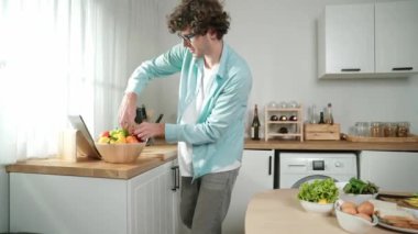 Mutlu baba yemek pişirirken müziğe geçiyor ve modern mutfakta öğle yemeği hazırlıyor. Aktif baba, sebze ve mutfak gereçleri ile çevrili sağlıklı yemek ya da salata yaparken şarkıyla dans ediyor. Pedagoji.