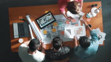 Yöneticinin planlara bakarken birlikte çalışmasını yukarıdan aşağıya izlemek. Mimar mühendis ekibinin fikir ya da planlarını paylaşırken dizüstü bilgisayar ve planlarla toplantı masasında durması. Sempozyum.