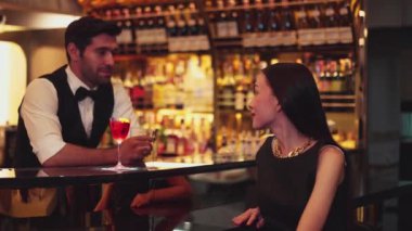 Barmen çiçekle süslenmiş karışık votka servisi yapıyor. Güzel bir konukla tezahürat yapıyor. Lüks tezgah barında oturuyor. Vinosity.