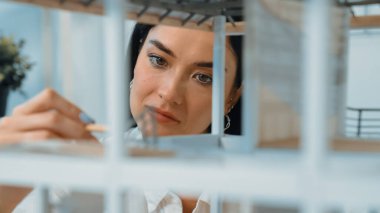 Ev modeli yapısını kendinden emin bir şekilde kontrol etmeye odaklanan genç, güzel, beyaz, yetenekli mimar mühendisinin yakın çekimi. Yaratıcı ve profesyonel tasarım konsepti. Portre. Tertemiz..