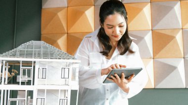 Tablet kontrol evi modelini kullanan güzel bir proje yöneticisi. Mimar mühendisinin portresi tabletteki veri analizini kullanarak bina inşaatını denetliyor. İş inşaat konsepti. Yönlendirici.