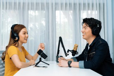 Gülümseyen radyo etkili sunucusu kulaklık takıyor kadın konuşmacı ile röportaj yapıyor sosyal medya internet sitesinden dinleyicilere bilgi paylaşıyor stüdyo kaydında sabah canlı yayın kanalı. İnfobahn.