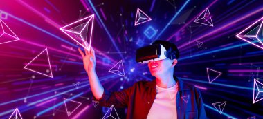 Afrikalı adam, VR kulaklık takıp parlak mavi ve pembe geometrik şekillerde dururken metaevreni keşfetmek için heyecanlanıyor. Oyuncu artırılmış gerçeklik gözlüğü kullanırken oyun oynuyor. Yaratıcılık.