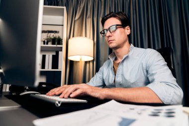 Akıllı iş adamı iş paragrafı dinamik pazarlama analizi planını analiz ediyor. Kağıt kağıtları ve bilgisayar monitörü raporlarını gece evdeki belge verileriyle karşılaştırmak için hazırlıyor. Bireysel.