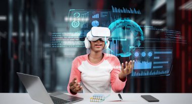 Masada kitap ve dizüstü bilgisayarla ödev yaparken metaevreleri birbirine bağlayan dizüstü bilgisayar ve artırılmış gözlük kullanan bir kız. Öğrenci holograma bakıyor ve yapay zekayı kullanıyor. Yaratıcılık.