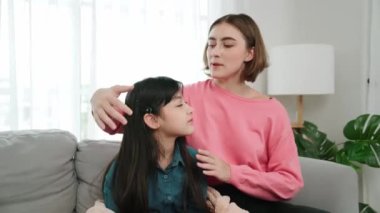 Kafkasyalı anne kızını kucaklıyor ve kanepede oturuyor ve alnından öpüyor. Mutlu anne oturma odasında sevimli Asyalı liseli kıza sevgi ve sevgi gösteriyor. Güzel bir aile birlikte vakit geçirir. Pedagoji.