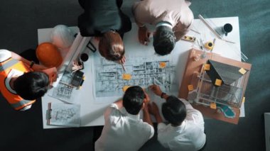 Becerikli mühendis ekibinin ev inşaatından bahsedişinin en alt görüntüsü. Mimar ya da tasarımcı grubunun planlar hakkında beyin fırtınası yapmak için tartışan ve yazan hava görüşü. Hizalama.