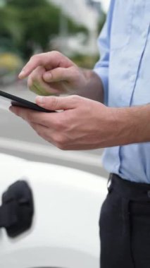 Modern iş adamı akıllı telefonun 3D hologramından batarya durumunu kontrol ederken EV arabasının şarj olan enerjisini kontrol ediyor. Gelecekteki EV otomotiv teknolojisinin yenilikçi teknolojik gelişimi. İnceleyin