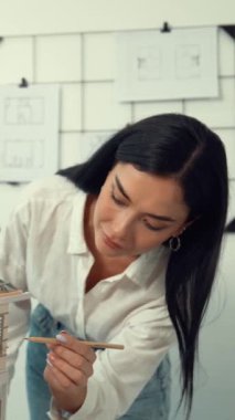 Genç, güzel ve zeki mühendisin yakın çekimleri modern ofiste duvarında taslak olan kalem kullanarak ev modelini ölçmeye odaklanıyor. Yaratıcı yaşam ve tasarım konsepti. Tertemiz..