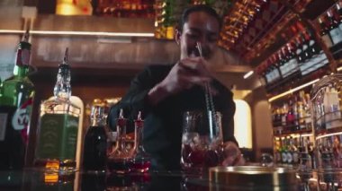 Zeki Asyalı barmen bardakta karıştırılmış alkol şurubunu buzla karıştırıyor. Çünkü kayanın üzerinde kamera var. Gece kulübünde taze kokteyl kokteylleri karıştırıyor. Vinosity.