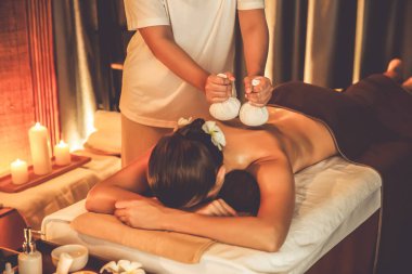 Sıcak bitkisel top spa masaj vücut tedavisi, masör kadın vücuduna nazikçe şifalı bitki torbası bastırıyor. Aromaterapi tesisinin sakinliği ve dinginliği kaplıca salonundaki mumların sıcacık ışığında. Sessiz.