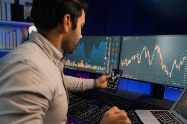 Akıllı tüccar işadamı, karanlık oda gecesinde neon ışıklı ofisteki arama pazarında yüksek kârla ekranda bilgisayar ve bilgisayar üzerinde dinamik borsa yatırımları üzerinde yoğunlaşıyor. Tahmin et..