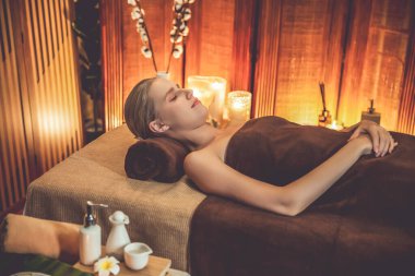Beyaz kadın müşteri stres önleyici spa masajının keyfini çıkarıyor ve lüks otel ya da otelde sıcak mum ışığında güzellik teniyle eğleniyor. Sessiz.