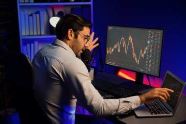 Akıllı tüccar işadamı, karanlık oda gecesinde neon ışıklı ofisteki arama pazarında yüksek kârla ekranda bilgisayar ve bilgisayar üzerinde dinamik borsa yatırımları üzerinde yoğunlaşıyor. Tahmin et..