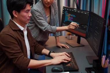 Bilgi teknolojisi geliştiricileri modern ofisteki neon ışık odasında verileri çevrimiçi olarak çalıştıran akıllı web sitesi geliştirme kodlayıcı sistemine işaret ediyorlar. İnfobahn.