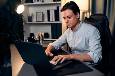 Akıllı iş adamı, gece vakti mavi perde arkasında iş hedefi olan finansal teknoloji veri raporlarını analiz etmek için veritabanı stoklarını araştırmak üzere dizüstü bilgisayarda uzaktan çalışıyor. Bireysel.