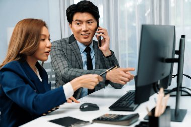 İş ortağıyla cep telefonundan arayan işadamı bilgisayardaki kadın iş arkadaşıyla hisse senedi değer veri tabanını hesaplarken şirket değerini analiz ediyor ya da güncel alım yapıyor. İnfobahn.