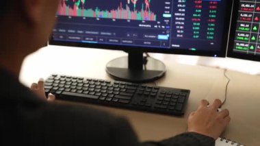 Borsa pazarlamasını analiz eden bir borsa yatırımcısı. Monitörlere bakıyor. Zarar ve kazanç ve kazanç için mum bar fiyatlarını analiz ediyor. Filizlenen