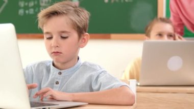 Çeşitli çocuklar yazılım sistemini programlarken beyaz çocuk dizüstü bilgisayarda çalışıyor. Öğretmen ve öğrenci sorunları çözmek ve kodlama mühendisliğini desteklemek için erkek bilgisayar ekranına bakıyor. Pedagoji.