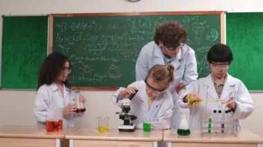 Kafkasyalı zeki öğretmen, meraklı öğrencilerin laboratuardaki deney kabına renkli sıvı dökmesini destekler. Yaratıcı çocuklar deney yapmaya ve biyokimyasal örnekleri incelemeye konsantre olurlar. Pedagoji.