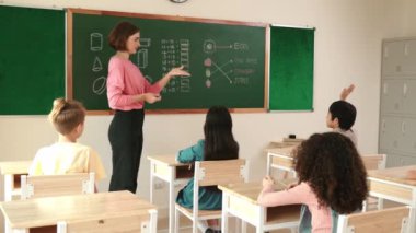 Enerjik Asyalı çocuk elini kaldırdı ve tahtaya cevap yazmak için gönüllü oldu. Öğretmen, mutlu öğrenci tebeşir alırken ve sınıfın önünde yürürken soruyu cevaplamak için gönüllü olmayı talep ediyor. Pedagoji.