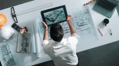 Tablet 'teki proje planına bakan yetenekli bir mimarın en iyi görüntüsü. İnşaat mühendisinin planlama görüntüsü güvenlik kaskı ve dizüstü bilgisayarla toplantı odasının planlarını kontrol ederken. Hizalama.