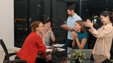 Mutlu iş adamları el çırpıyor ve başarılı projeyi kutluyor. Profesyonel iş adamlarından oluşan bir grup, iyi haberleri kutlamak ve şehir manzarası ile gece ofisinde terfi almak için alkış tutuyor. İzleme