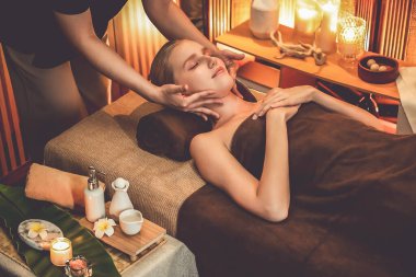 Beyaz kadın stres önleyici kafa masajı yapmaktan ve lüks otel veya otelde sıcak mum ışığında yüz güzelliği eğlencesi yapmaktan zevk alıyor. Sessiz.