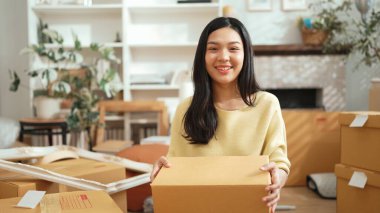 Genç bayan işyeri sahibi dükkanda dikilirken elinde karton tutuyordu. Teslimat ya da nakliye işlemleri için hazırlık yaparken paket ve kutu taşıyan çekici, mutlu girişimci. Myrmidon.