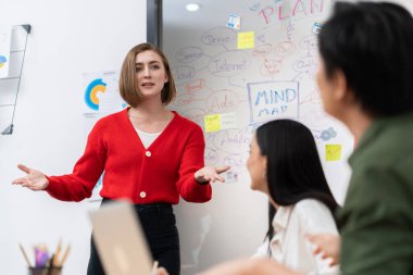 Kafkasyalı genç bir iş kadını, pazarlama stratejisini zihin haritası kullanarak sunuyor, soruları kendinden emin bir şekilde cevaplarken grafiğini çiziyor. Takım çalışması, beyin fırtınası, tartışma konsepti. Tertemiz..