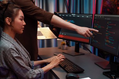 Modern ofisteki neon ışık odasında bilgi ağını gösteren dizüstü bilgisayarla iki ekranda veri çalıştıran akıllı web sitesi geliştirme kodlayıcı sistemini tartışan IT geliştiricilerinin ciddiyeti. İnfobahn.