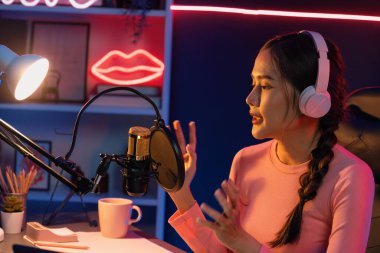 Geceleri podcast 'te olumlu konuşmalar yapan, pembe neon ışıklı modern stüdyoda sunum için dizüstü bilgisayar kullanan, gülümseyen, genç, güzel Asyalı bir etkileyiciydi. Taktik.