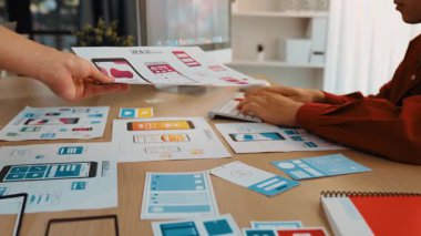 Mobil uygulama için kullanıcı arayüzü prototipini ofis çalışanlarına sunan harika bir şirket çalışanı. UX UI tasarımcısı kağıt üzerinde simge tasarımının işlevini açıklıyor. Sinerjik