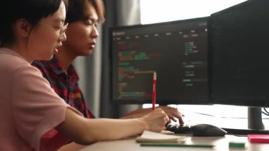 Yavaş çekim arkası yazılım geliştirici mühendisi bilgisayar programlama için birlikte çalışarak hata ayıklama kodunu çözüyor, ofiste monitörde karmaşık algoritmaları çözüyor. Filizlenen