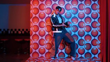 Asyalı break dansçı serbest stile geçiyor ve balon arka planlı kameraya bakıyor. Profesyonel hippi gündelik kıyafet giyer ve gözlük takar. Mutluluk.