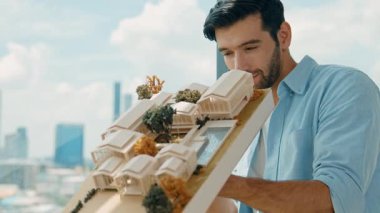 Yetenekli genç beyaz mimarın sol ve sağ taraftaki asansör evi modelini yakından incele ve hata noktasını gökdelen ile kontrol etmeye odaklan. İzleme