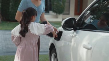 Evde şarj edilen elektrikli bir araçla okuldan yeni dönen anne ve kızın ilerici yaşam tarzı. Elektrikli araç, sürdürülebilir temiz enerjiyle çalışıyor..