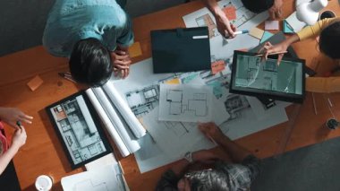 Yetenekli iş adamlarının tablet tutması ve planlara bakması. Masada dizüstü bilgisayarla dururken mimarın tasarım ve planlama bölümünün havadan görüntüsü. Sempozyum.