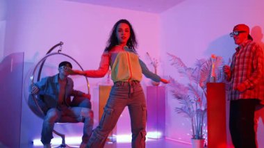 İspanyol hipster renkli kıyafetler giyer ve serbest stil müziğe el sallar. Profesyonel break dansçı neon ışıklarıyla ve modern stüdyo arkadaşlarıyla coşkuyla dans ediyor. Mutluluk.