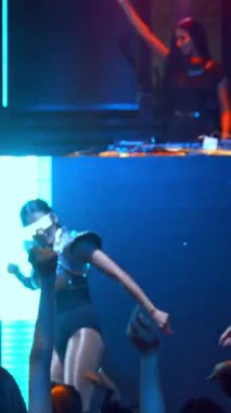 Bir grup insan disko gece kulübünde DJ 'in sahnede çaldığı müzikle dans ediyor. Yeni yıl partisi ve gece hayatı konsepti .