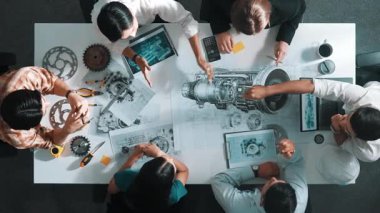 Üstten görünüşlü akıllı mühendis ekibi metal teçhizatlı, hesap makineli, yapışkan notlu türbin motor yapısı hakkında konuşuyor. Bir grup teknisyen toplantıda not alıyor. Hizalama.