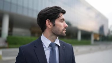 Binada dikilirken kameraya bakan yetenekli bir iş adamı. İş elbisesi giyerken kameraya gülümseyen başarılı adamın yakın çekimi. Mutlu yönetici kameraya bak. İş için. Sevinçli..