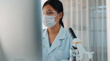 Laboratuvar kimya araştırmacısı mikroskop ve dizüstü bilgisayar kullanarak yeni ilaç ya da tedavi geliştirir. Bilimsel uzmanlığa ve laboratuvar mikrobiyoloji ekipmanlarına sahip sağlık teknolojisi. Ağır çekim. Katı.